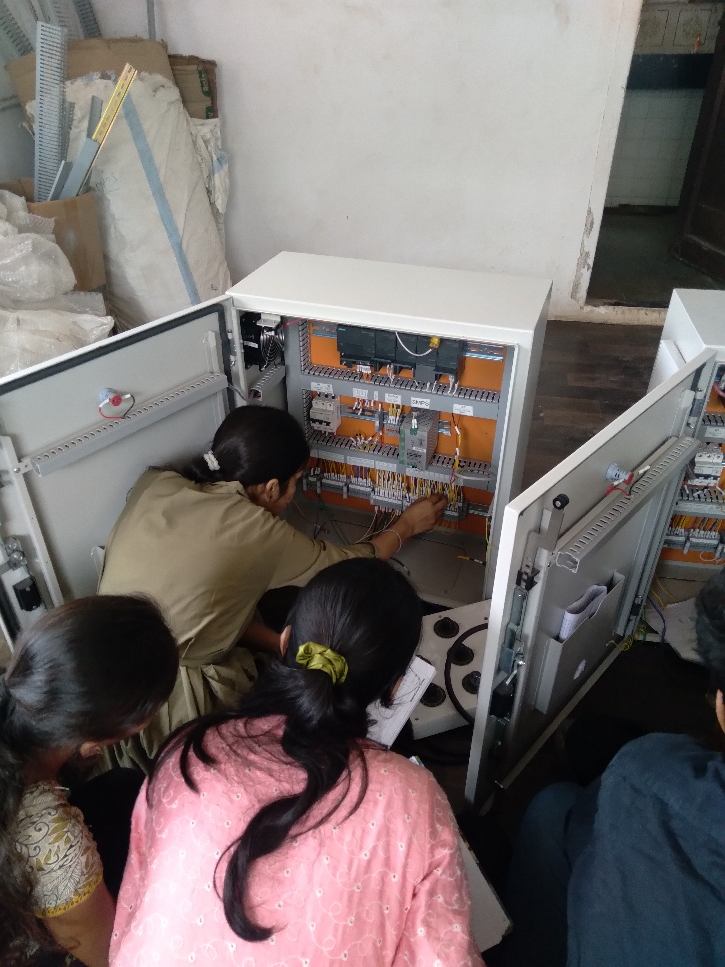 Trainees wiring PLC control panels during a panel-building session